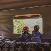 Two boys look out of the window from inside a Camp365
